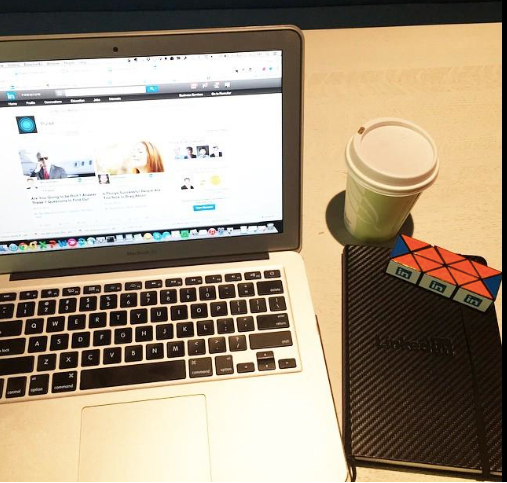 A founder's desk with an open laptop on LinkedIn, a notebook, and coffee during a content batch day
